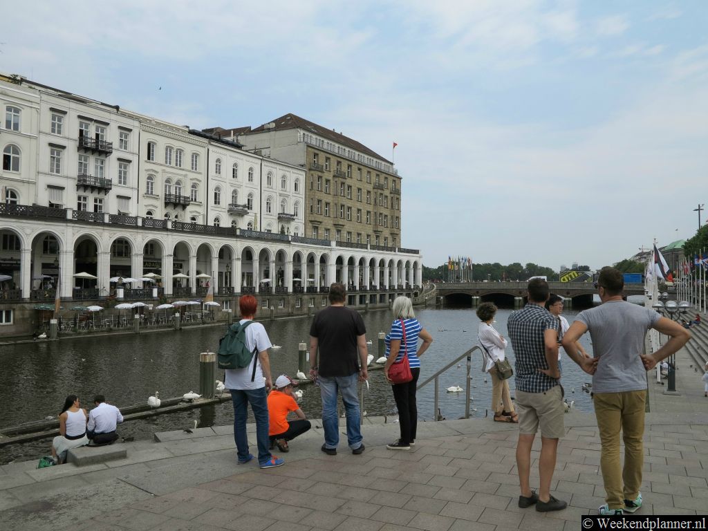 Vanaf het plein Rathausmarkt heb je een mooi uitzicht op de overdekte winkelstraat Alsterarkaden en de sluis bij het meer de Alster.